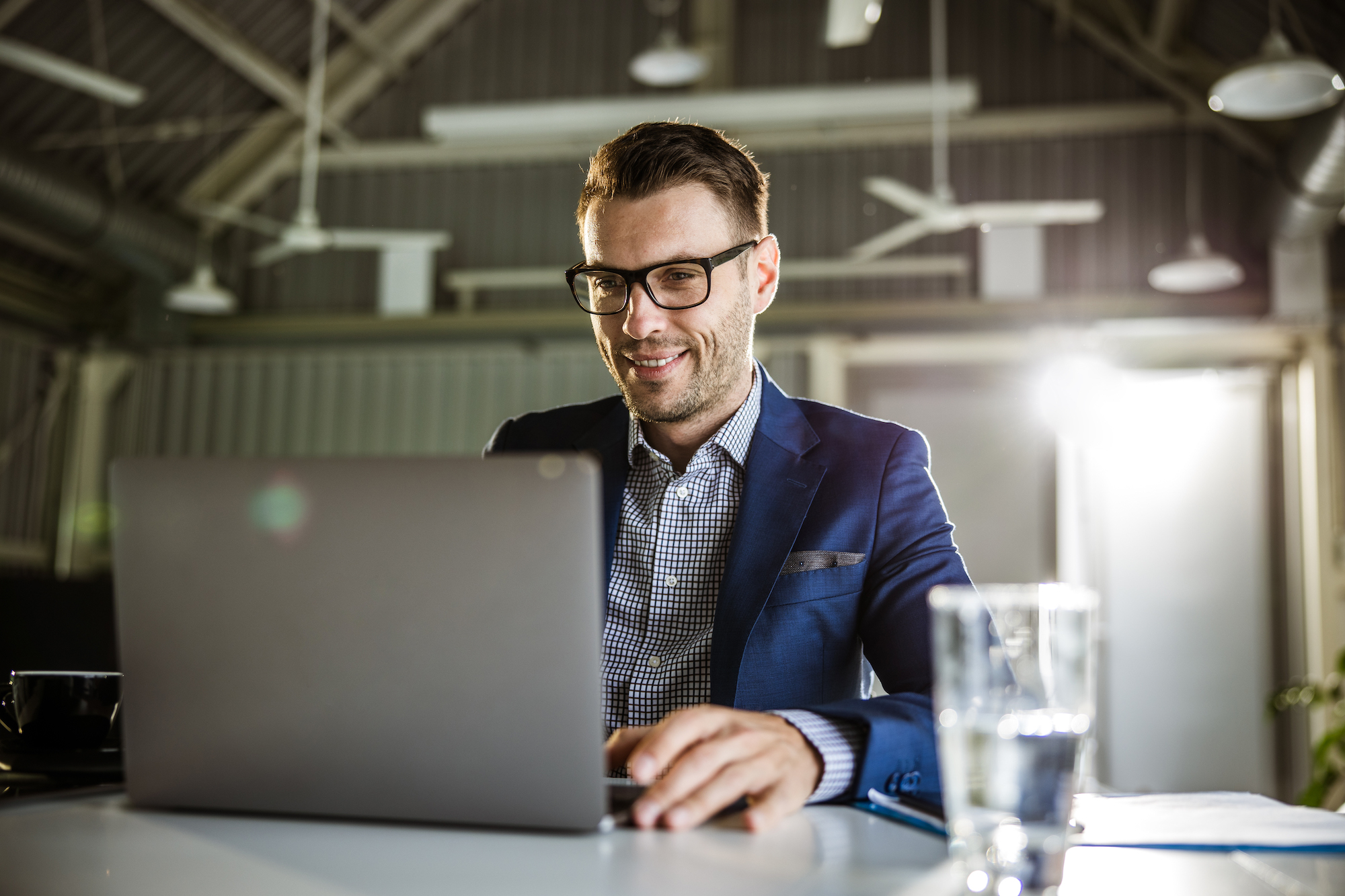 Young happy businessman working on laptop in the office.